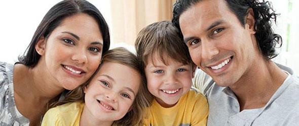 Family with two kids all smiling at camera