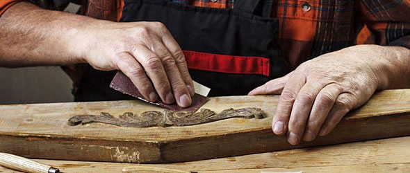 Wood worker sanding an old piece of wood