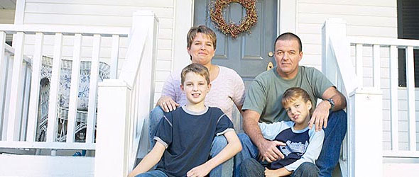 Parents with kids sitting on porch steps looking at camera